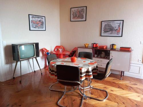 a living room with a table and a television at Vintage ,le paradis des enfants wifi draps parking free in Thiers