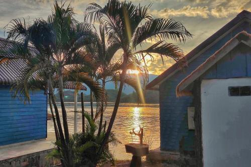 a palm tree next to a house with a view of the water at Sunset Nam Ngum resort in Vang Vieng