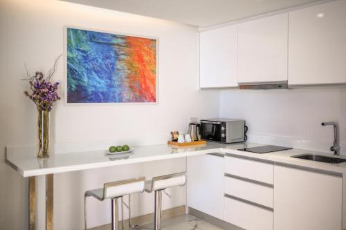 a kitchen with white cabinets and a painting on the wall at The Beachfront Hotel Phuket in Rawai Beach