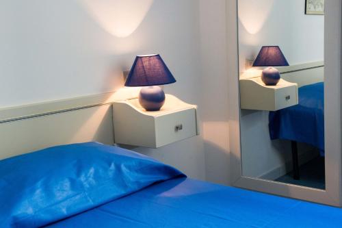 a bedroom with a bed and a mirror with a lamp at Le Bianche ville con patio privato a un passo dal mare in Torre Suda