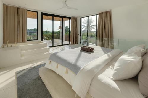 una camera bianca con un grande letto e ampie finestre di Sore Pererenan Residence Unit 1 a Canggu