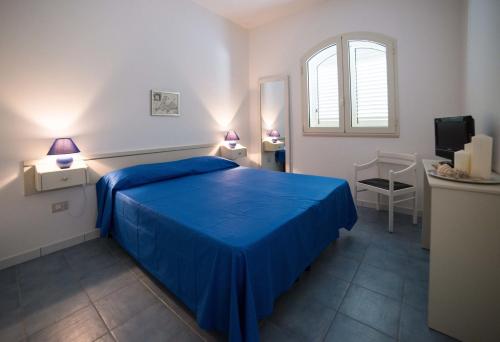 a bedroom with a blue bed and a window at Le Bianche in Torre Suda