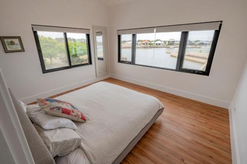 a bedroom with two large windows and a bed at Port Lane Townhouse in Geographe