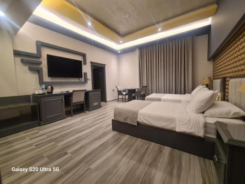 a bedroom with a bed and a desk and a television at Hisham Hotel in Amman
