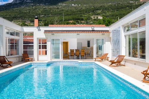 uma piscina com cadeiras e uma casa em Villa My Dream in Kastel Stari em Kaštel Stari