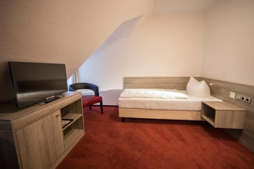 a bedroom with a bed and a flat screen tv at Altes Landhaus in Lingen