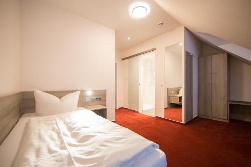 a bedroom with a white bed and a mirror at Altes Landhaus in Lingen
