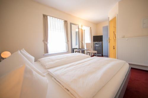 a large white bed in a room with a window at Altes Landhaus in Lingen