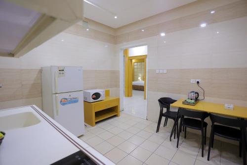 a kitchen with a refrigerator and a table and chairs at Hosta Serviced Apartments Al Malqa in Riyadh