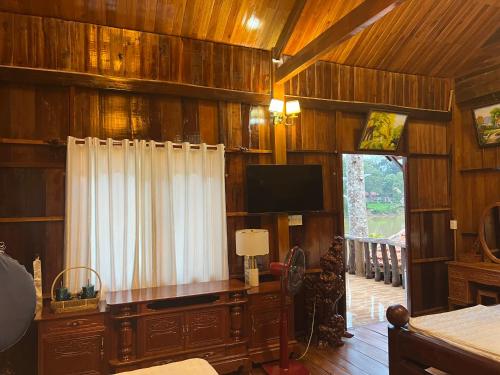 a living room with wooden walls and a flat screen tv at Cat Tien River Lodge in Cat Tien