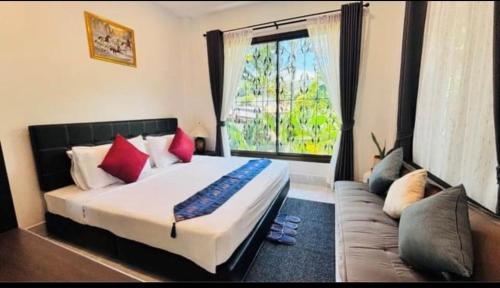 a bedroom with a bed and a couch and a window at Kata Sea Blue Villa in Kata Beach
