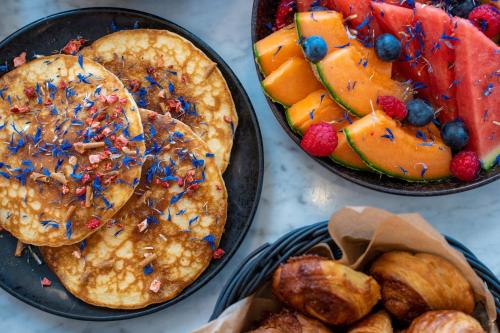 a table with two plates of pancakes and fruit at AC Hotel by Marriott Bella Sky Copenhagen in Copenhagen