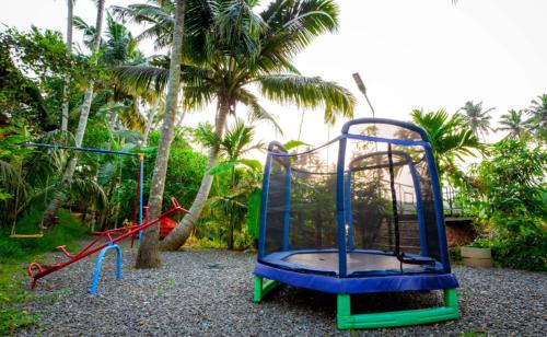 een speeltuin met twee schommels en een glijbaan bij Elite Inn Cholai Lake View Resort in Taingapatam