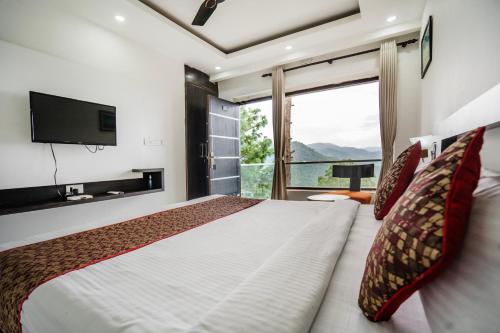 a bedroom with a large bed with a large window at The Golden Sunrise Hotel in Nainital