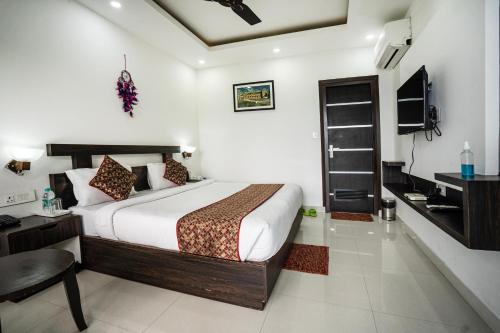 a bedroom with a bed and a desk and a television at The Golden Sunrise Hotel in Nainital
