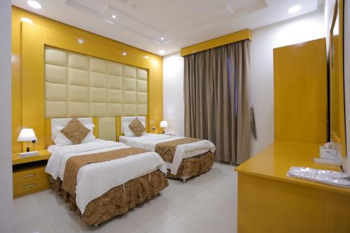 a hotel room with two beds and a mirror at Hosta Serviced Apartments Al Malqa in Riyadh