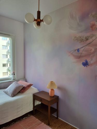 ein Schlafzimmer mit einem Bett und einer Lampe auf einem Tisch in der Unterkunft Vintage Glamour Suite, parveke, parkkipaikka in Helsinki