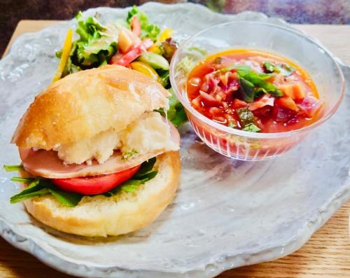 a plate with a sandwich and a bowl of salsa at HOTEL LT Kitchen Yugawara in Yugawara