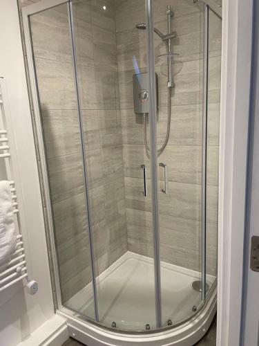y baño con ducha y puerta de cristal. en Ascot House Apartments en Peterborough