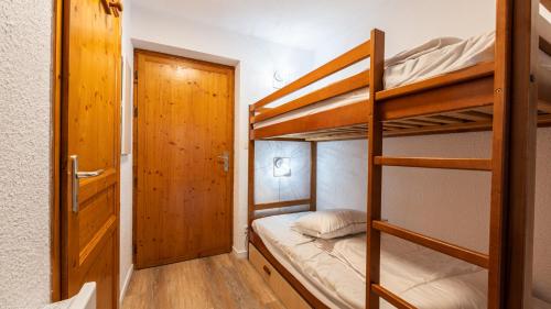 a bunk bed room with two bunk beds and a door at Les Eterlous 37- Appt skis aux pieds 4 pers in Morillon