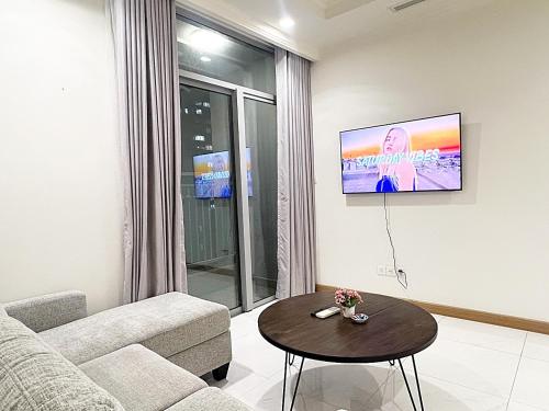 - un salon avec un canapé et une télévision murale dans l'établissement Luxury Apartment at Vinhomes Central, à Hô-Chi-Minh-Ville
