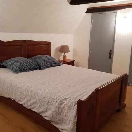 une chambre avec un grand lit avec une tête de lit en bois dans l'établissement Charmante maison de campagne, à Chasteaux
