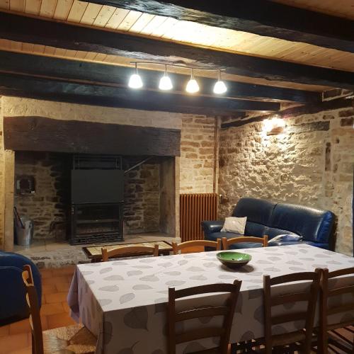 un salon avec une table et des chaises et une cheminée dans l'établissement Charmante maison de campagne, à Chasteaux