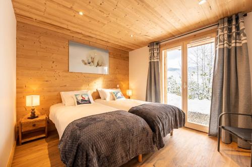 two beds in a room with a window at Chalet du Tricot - Vue sur le Mont Blanc in Saint-Gervais-les-Bains