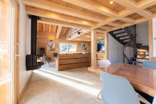 une salle à manger avec une table en bois et des chaises blanches dans l'établissement Chalet du Tricot - Vue sur le Mont Blanc, à Saint-Gervais-les-Bains
