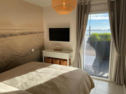 a bedroom with a bed and a view of the ocean at RÉF 231 - PORT-LOUIS appartement type 2 pleine vue Petite Mer avec terrasse, parking et garage dans résidence récente in Port-Louis