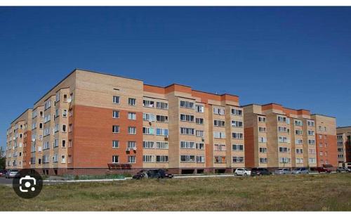 a large brick building with cars parked in a field at 5 мин международный аэропорт in Prigorodnyy