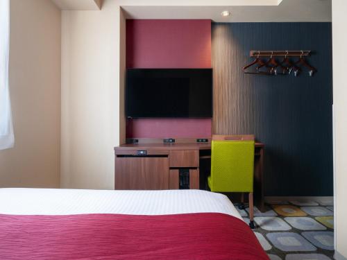 a hotel room with a bed and a desk and a tv at the b sapporo in Sapporo