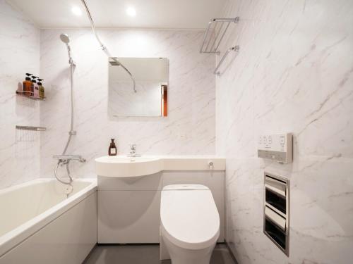 a white bathroom with a toilet and a sink at the b sapporo in Sapporo