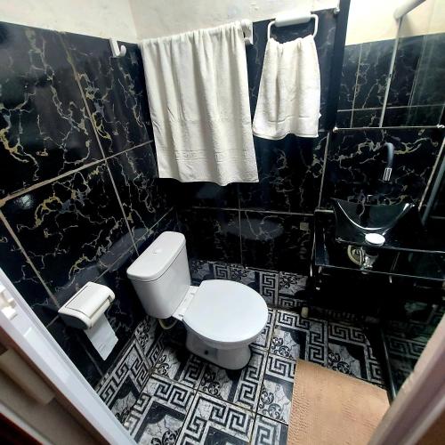 a black and white bathroom with a toilet and a sink at Residência Thomas in Itacaré
