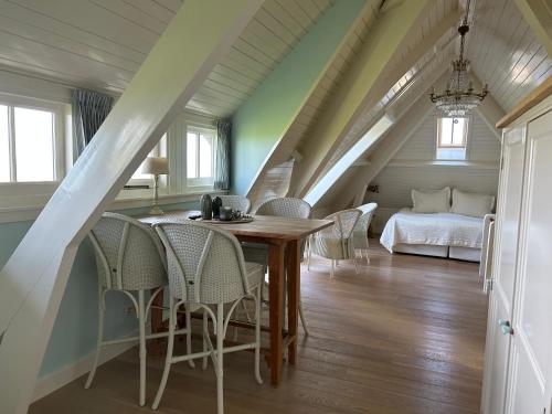 una sala da pranzo con tavolo, sedie e letto di Villa Nieuwland B&B a Den Oever