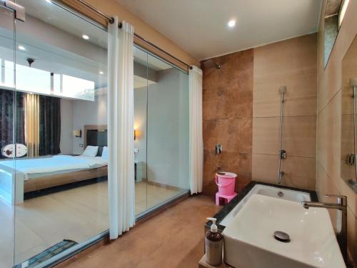 a bathroom with a tub and a bedroom with a bed at The Kanila Resort in Karjat