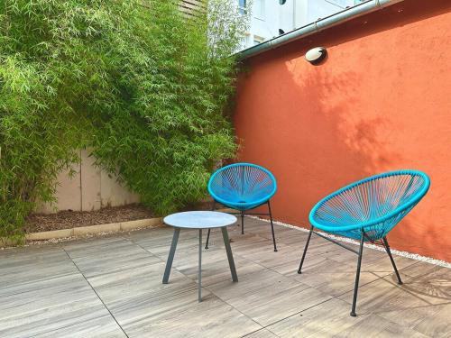 duas cadeiras azuis e uma mesa ao lado de uma parede em Le Patio de Loiseau em Le Mans