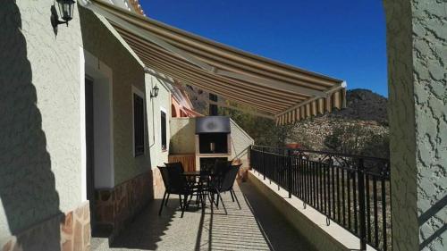 Un patio con sillas y una mesa en el balcón. en Casa Rural Puente Del Segura, en Elche de la Sierra