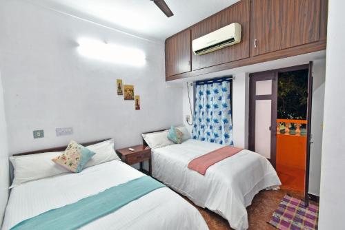 a bedroom with two beds and a tv and a window at Coral Home Stay in Puducherry