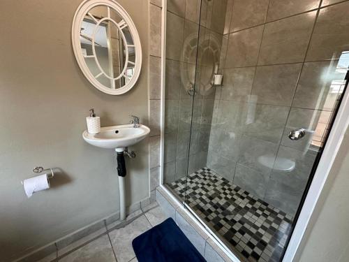 a bathroom with a shower and a sink and a mirror at 15 On Natorp in Polokwane