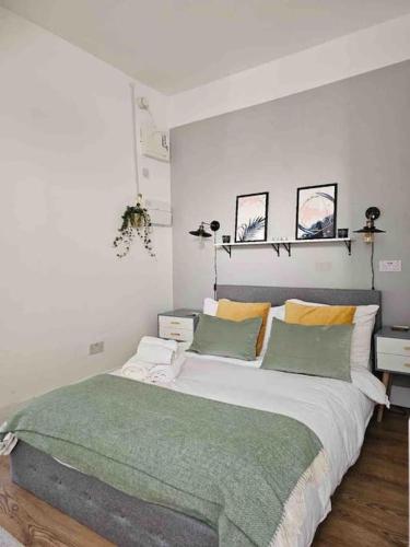 ein Schlafzimmer mit einem großen Bett mit grünen und gelben Kissen in der Unterkunft Putney Thames garden flat in London
