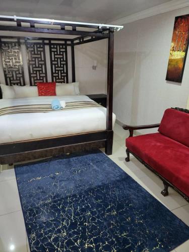 a bedroom with a bed and a red couch at At Blackwood Guesthouse in Pretoria