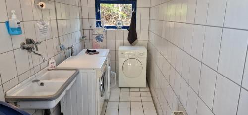 uma pequena casa de banho com uma máquina de lavar roupa e um lavatório em Ferienwohnung 'Gelting' - Refugium Pottloch Ostsee em Kronsgaard