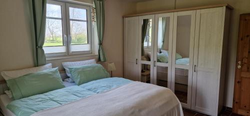 um quarto com uma cama e duas janelas em Ferienwohnung 'Gelting' - Refugium Pottloch Ostsee em Kronsgaard