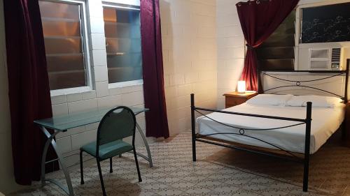 a bedroom with a bed and a chair and a desk at Asylum Cairns Share House in Cairns