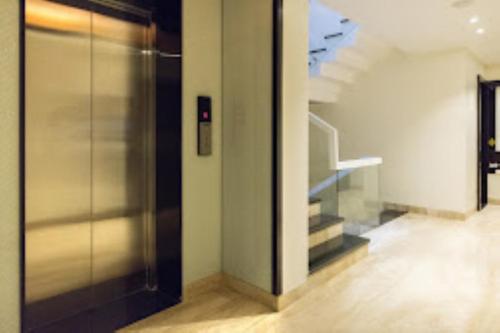 a hallway with a glass door and stairs in a building at Hotel Sangat Regency in Bhopal