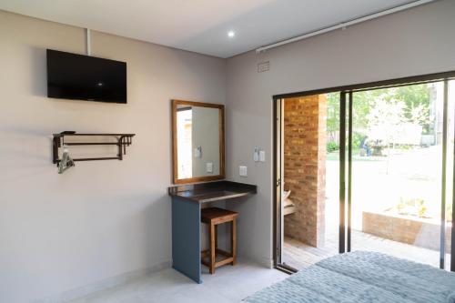 a bedroom with a mirror and a tv on the wall at Opstal Gastehuis in Potchefstroom