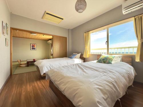 a bedroom with two beds and a large window at Hotel NALU　ホテルナル in Kannoura