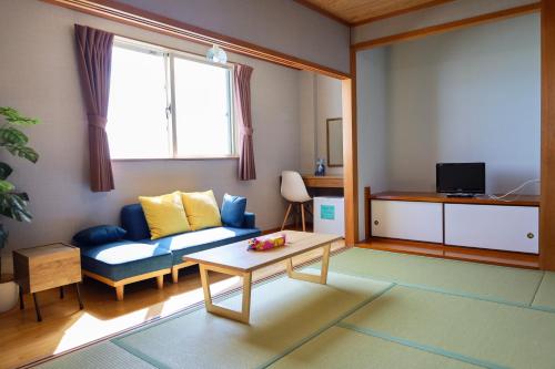 a living room with a couch and a table at Hotel NALU　ホテルナル in Kannoura