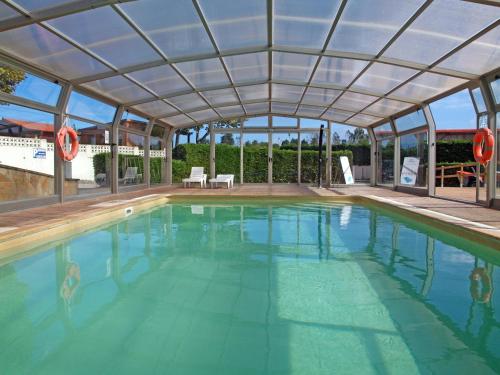 a large swimming pool with a large roof at Bungalows Playa de Oyambre in San Vicente de la Barquera